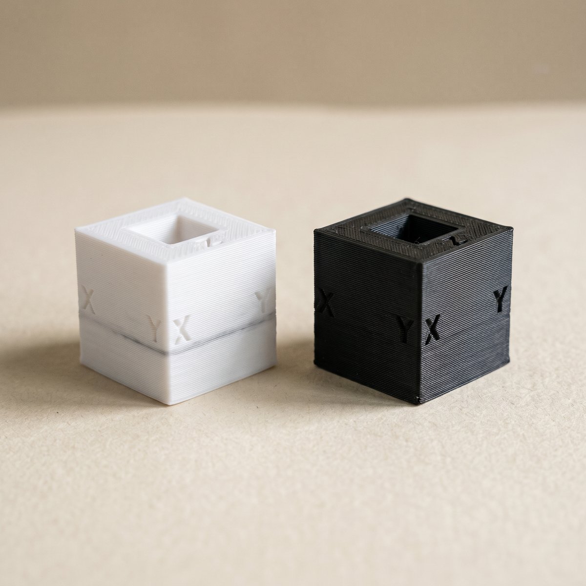 White and black printed test cubes showing K2 Plus color bleed as gray streaks in the white cube's lower layers