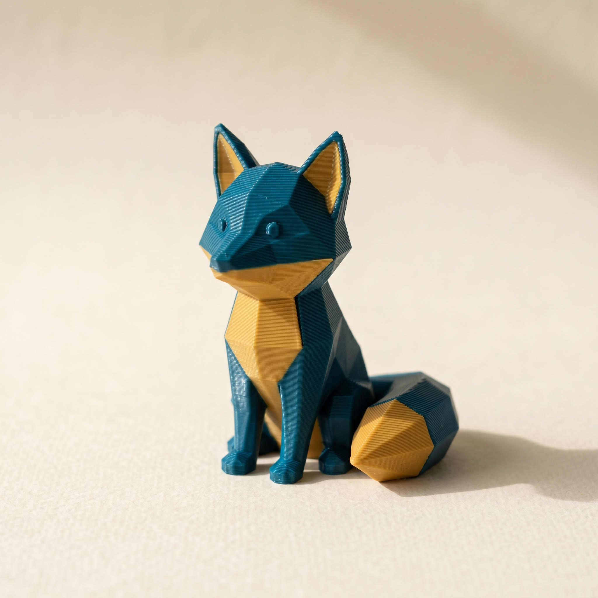 A low-poly 3D printed fox figurine in teal and mustard filament, the kind of two-color model you might want to recolor