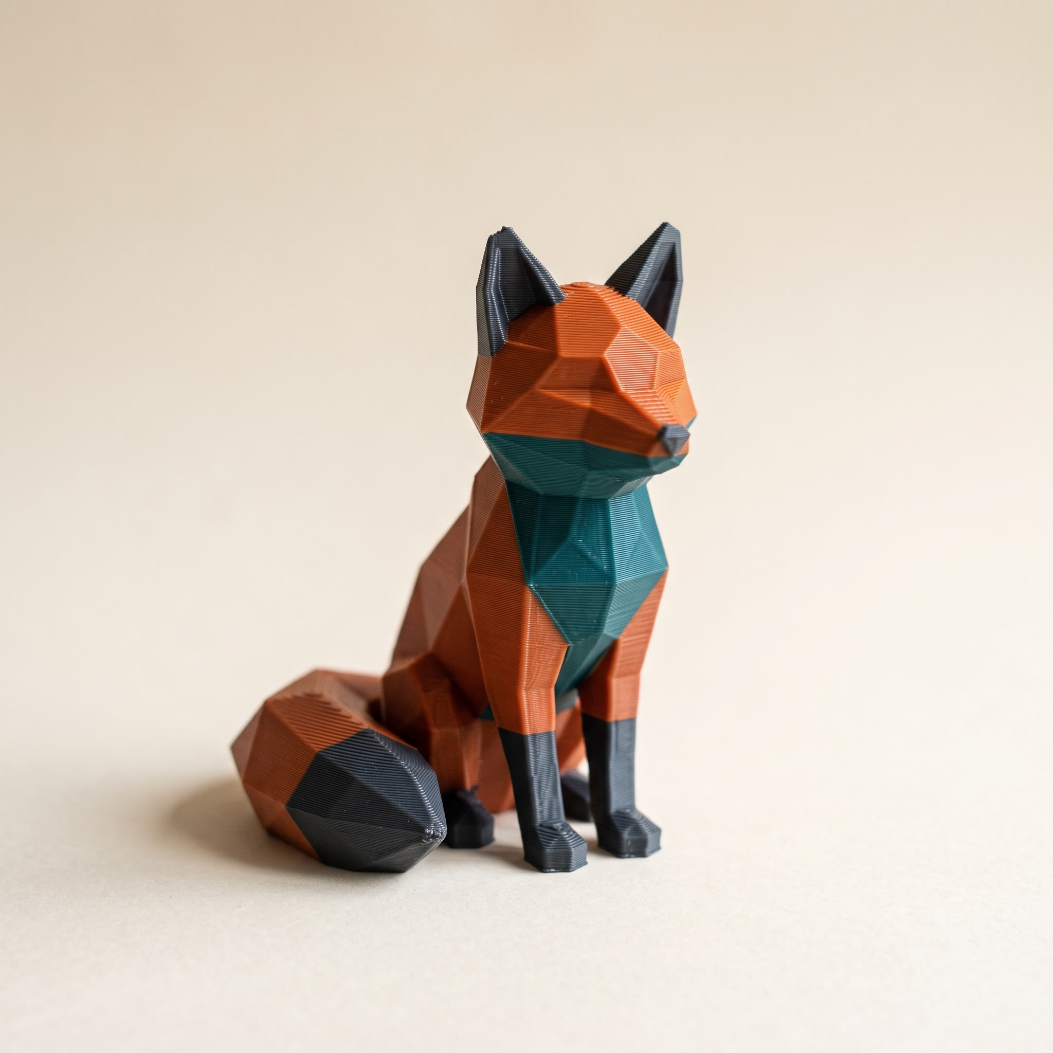 A multi-color 3D-printed low-poly fox figurine in orange, teal and charcoal filament, the kind of model an STL to OBJ conversion cannot color