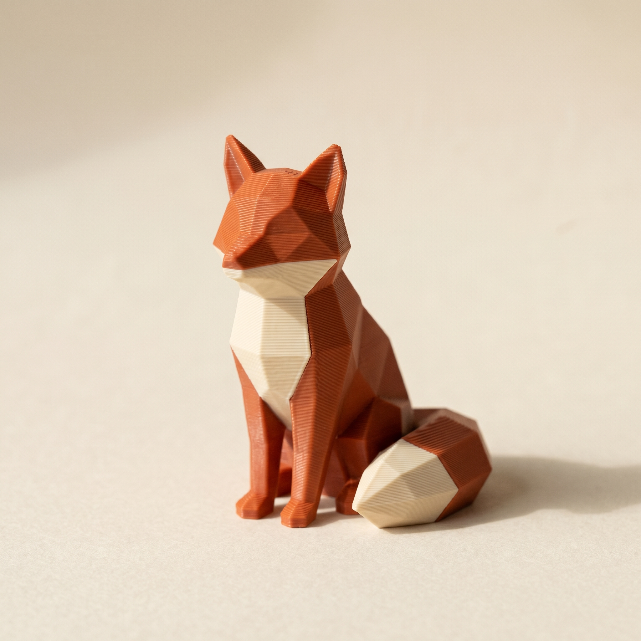 A multi-color 3D printed low-poly fox figurine in matte burnt-orange and cream filament with crisp color boundaries between regions