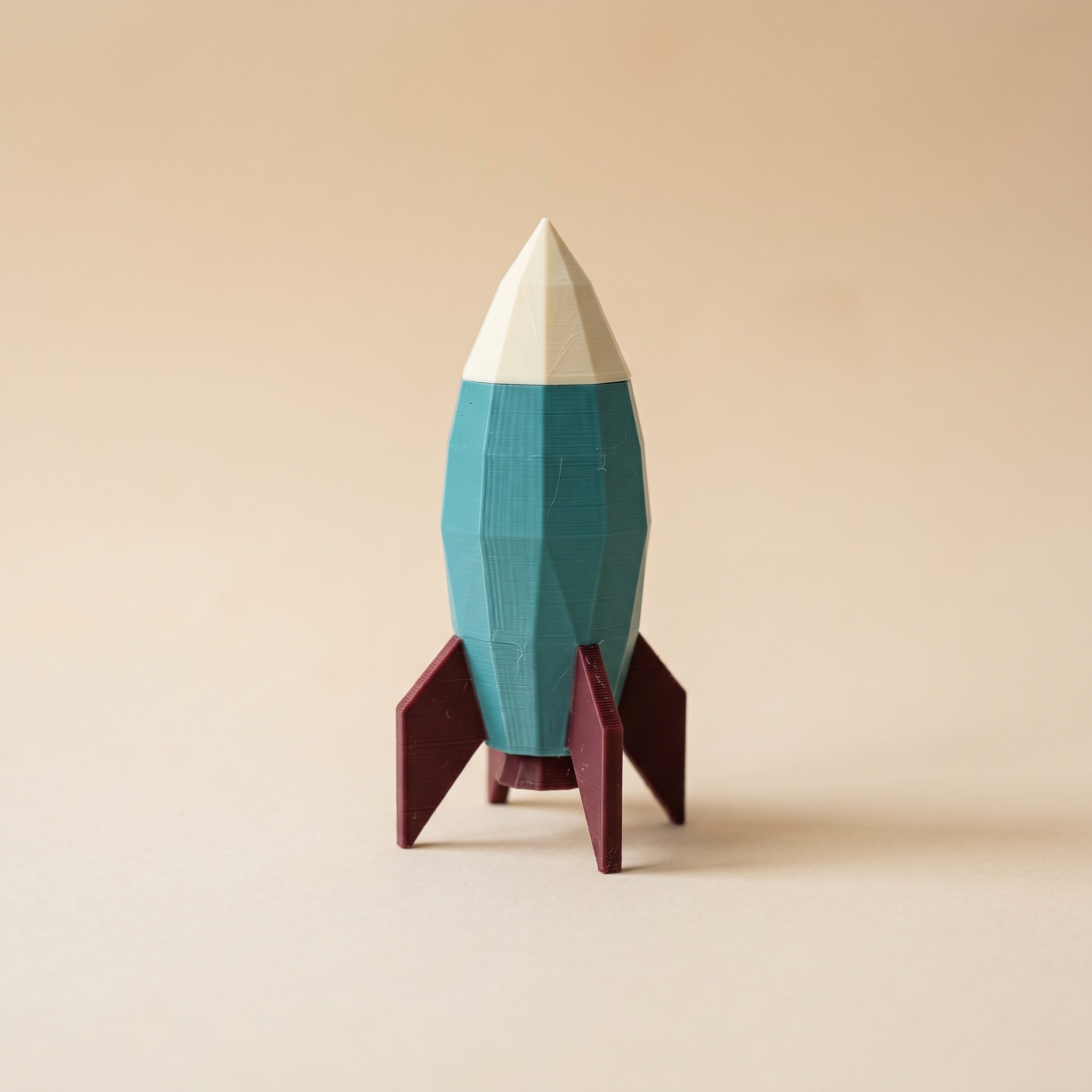 A multi-color 3D printed low-poly rocket in teal, burgundy, and cream — a classic supports-required shape